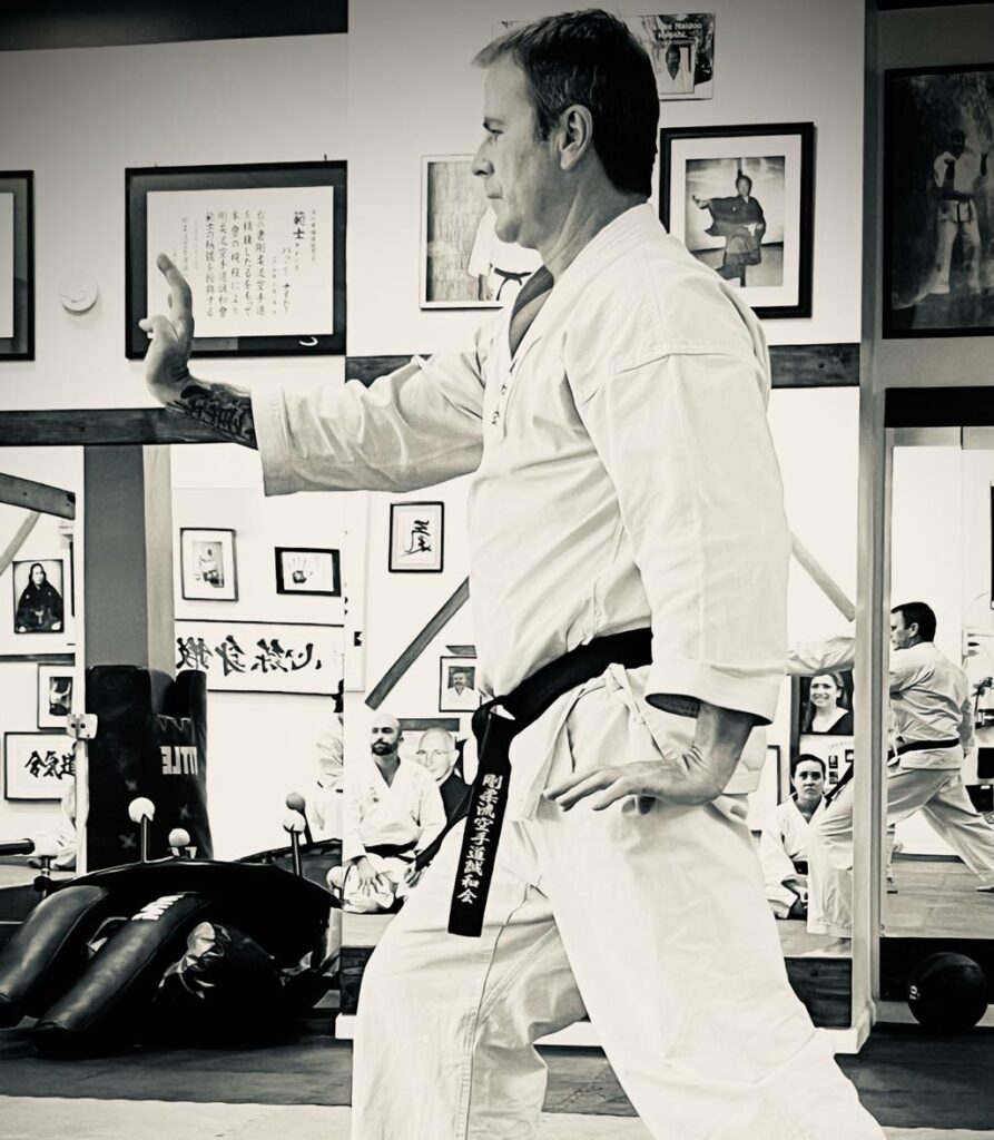 Senpai Mike Lavin, 4th Dan, demonstrating a defensive karate stance in a traditional white gi at the Karate of LA dojo.