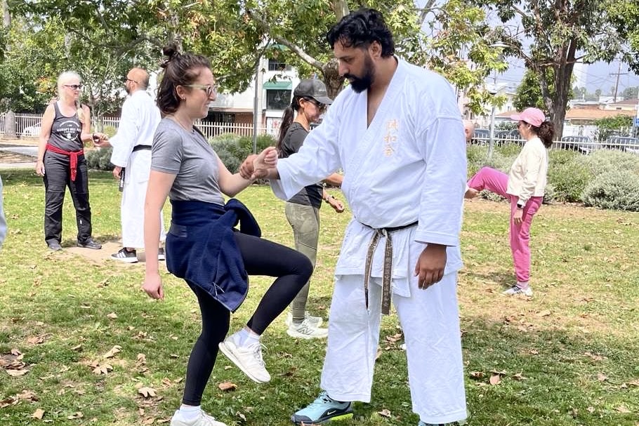 A student and an instructor practice a wrist control technique at an outdoor park in Santa Monica.