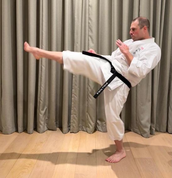 ryan-condal-goju-ryu-seiwa-kai-karate-black-belt 4th dan black belt Ryan Condal executing a traditional martial arts front kick in a white gi.