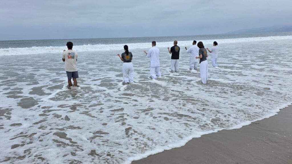 Traditional Goju Ryu Ocean Training Martial arts students training calf-deep in crashing ocean waves to test balance and stability as part of traditional karate training tips.