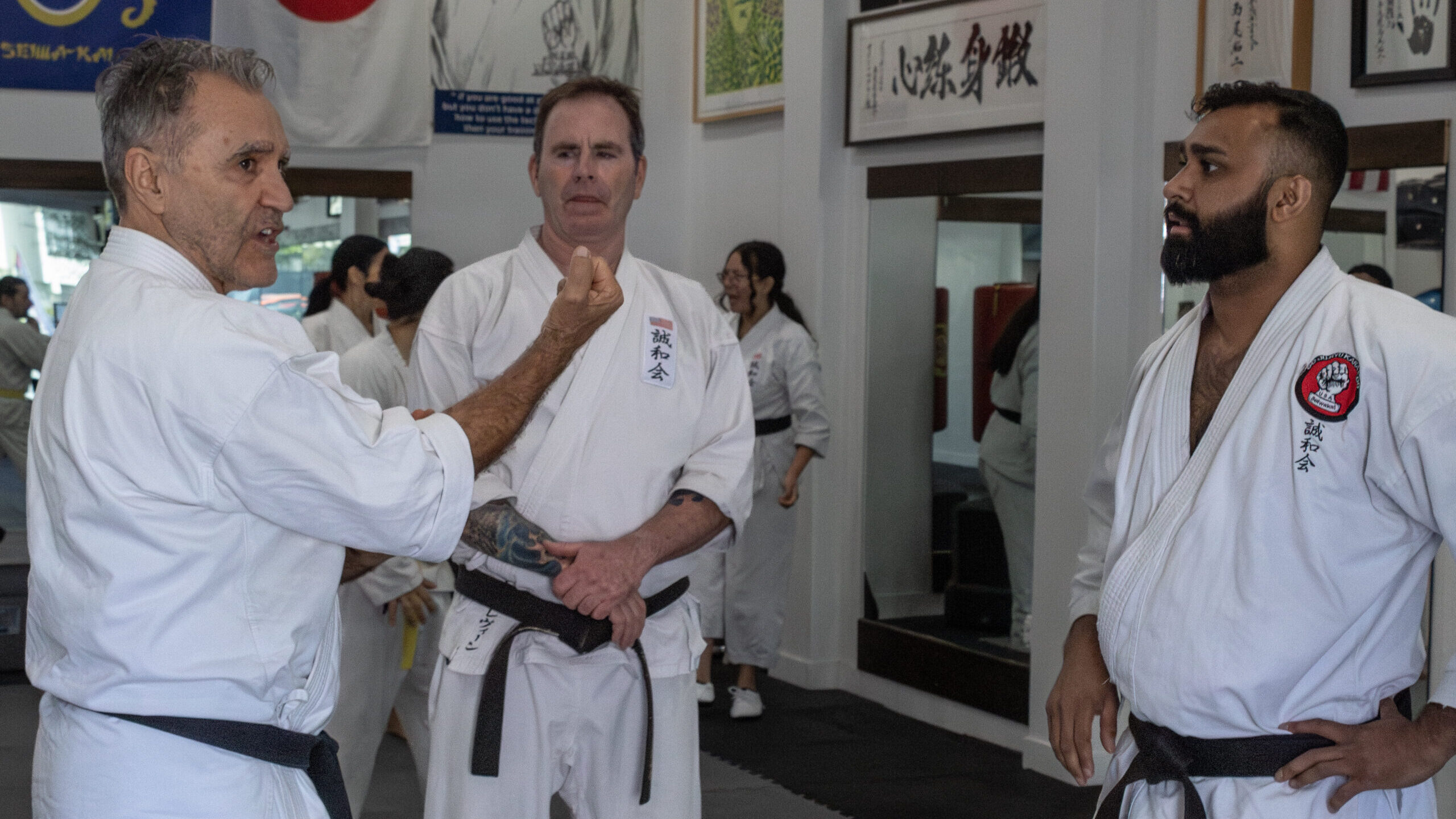 Senior Goju-Ryu black belt instructors collaborating and analyzing traditional karate hand mechanics during an advanced training session at Karate of LA.