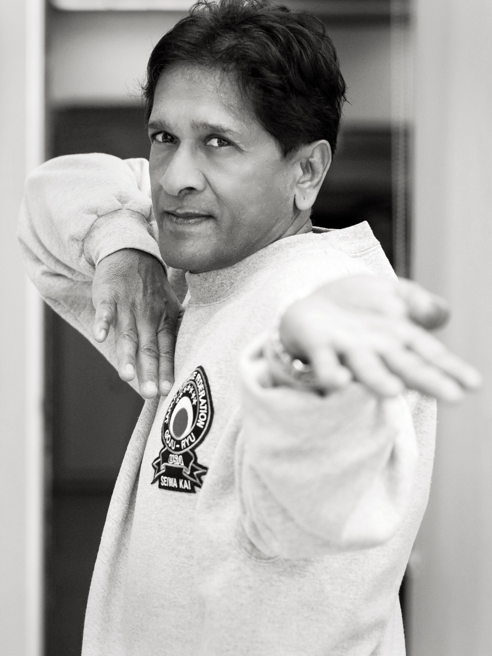 Black and white portrait of Vassie Shihan executing a focused, traditional martial arts stance in a Goju-Ryu Seiwa-Kai sweater.
