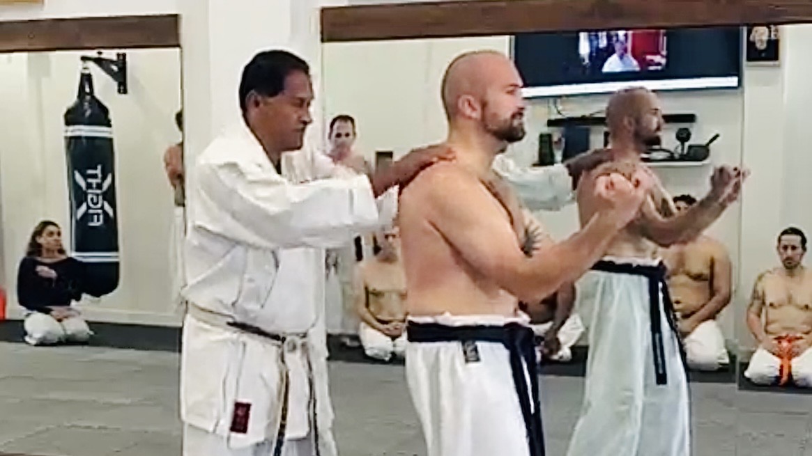 Shihan Vassie Naidoo striking Senpai Conrad Williams on the shoulders during traditional Goju-Ryu Sanchin shime testing at Karate of LA.