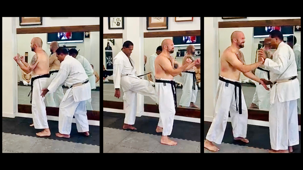 Shihan Vassie Naidoo performing Sanchin shime on Senpai Conrad Williams, testing rooted knee alignment and adductor tension in Sanchin-dachi stance.