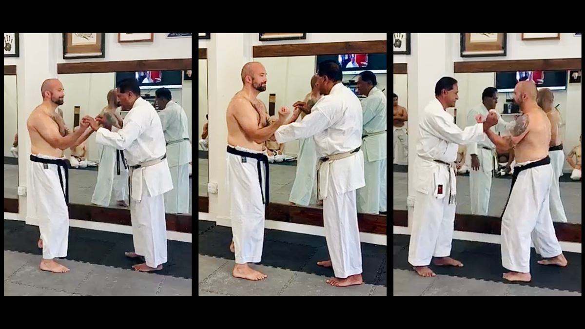 Shihan Vassie Naidoo testing upper frame alignment, depressed shoulders, and center of gravity balance on Senpai Conrad Williams during Sanchin Kata.